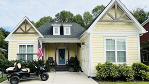 Una casa a due piani con un portico anteriore, un garage e un prato.