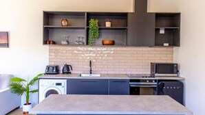 Cocina compacta con lavadora, microondas y cafetera.