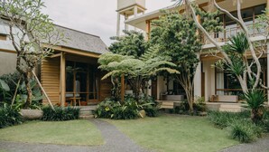 A modern house with a covered porch, a small tower-like structure, and lush greenery. - Wana Karsa Ubud Hotel (Ubud)