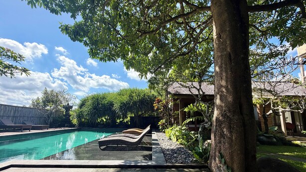 A swimming pool with lounge chairs, surrounded by lush greenery and a wooden structure. - Wana Karsa Ubud Hotel (Ubud)