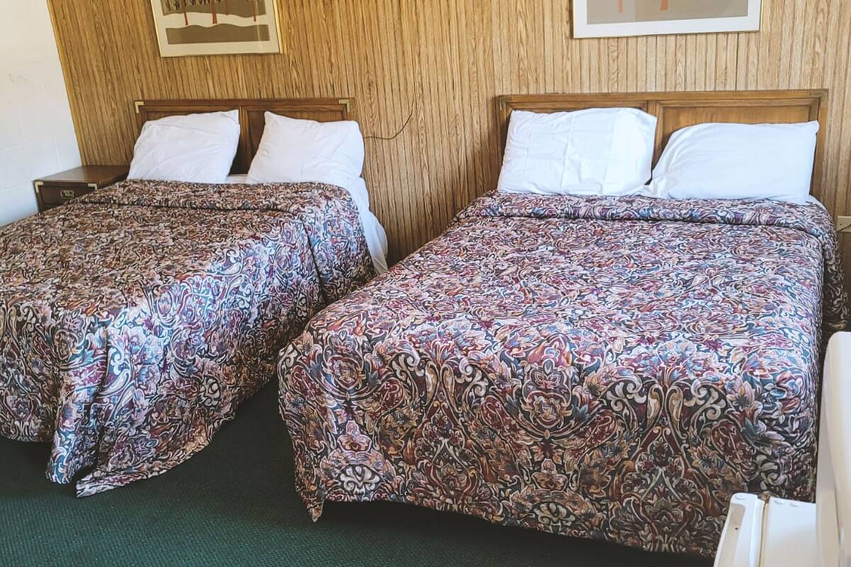Deux lits simples avec des couvre-lits à motifs, des têtes de lit en bois et des oreillers blancs.