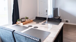 Un comedor moderno con una mesa de mármol, sillas negras y una mesita de madera con plantas.