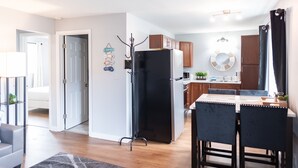 Una cocina moderna con armarios de madera, un refrigerador negro y un comedor con dos sillas.