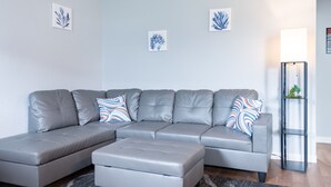 Una sala moderna con un sofá seccional gris, un reposapiés a juego y cojines decorativos.