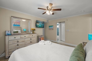 A bedroom with a bed, dresser, ceiling fan, and artwork on the walls. - Siesta Key Base | Walk to Beach | Free Activities (Sarasota)
