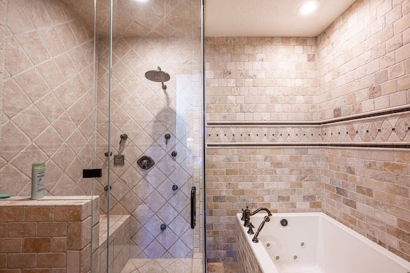 A bathroom with a glass-enclosed shower, a bathtub, and tiled walls.
