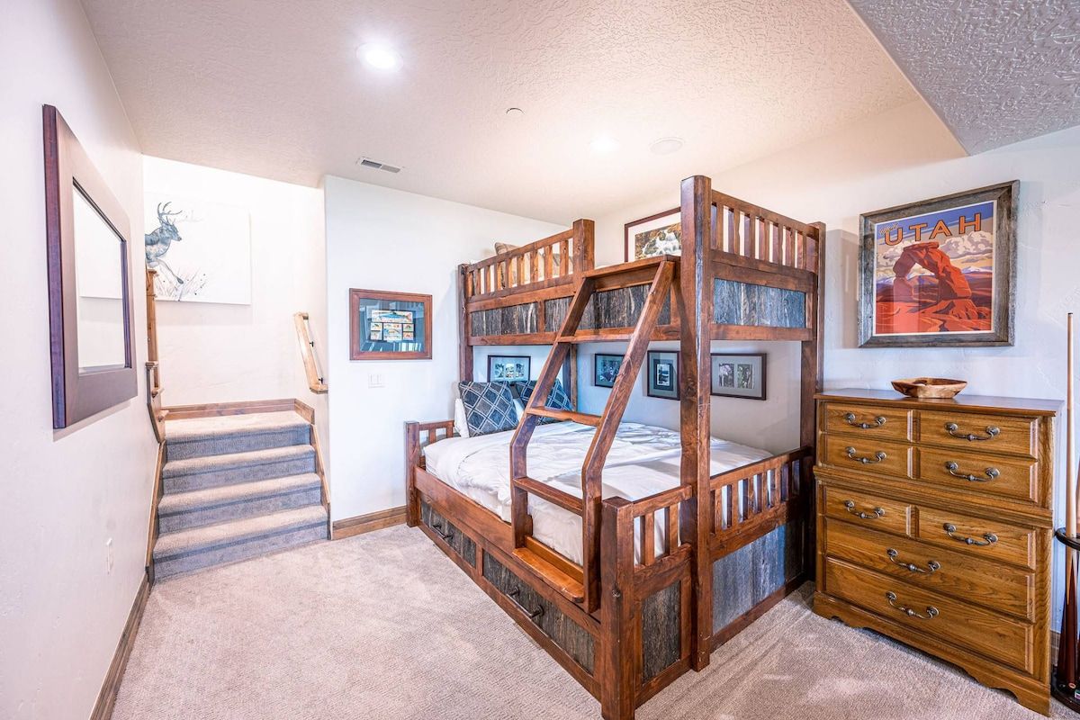 A bedroom with a bunk bed, a wooden dresser, and a staircase.
