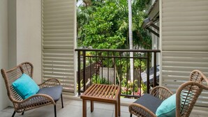 A balcony with wicker furniture and a view of greenery. - Seascape Holidays at Seascape Temple - Studio (Douglas)