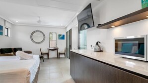 A modern hotel room with a bed, a small desk, a TV, and a kitchen area with a microwave. - Seascape Holidays at Seascape Temple - Studio (Douglas)