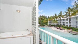 Ein Balkon mit Badewanne, Pool und Palmen.