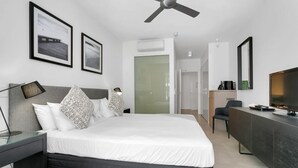 Ein modernes Hotelzimmer mit Bett, Nachttisch, Schreibtisch und Fernseher.