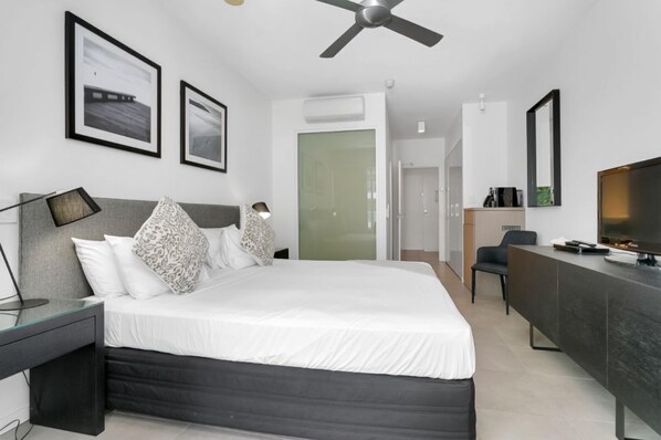 A modern hotel room with a bed, bedside table, desk, and TV. - Seascape Holidays at the Beach Club Studio Spa Room (Douglas)