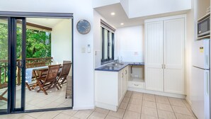 Una cocina moderna con armarios blancos, encimera azul y una zona de comedor con sillas y mesa de madera.