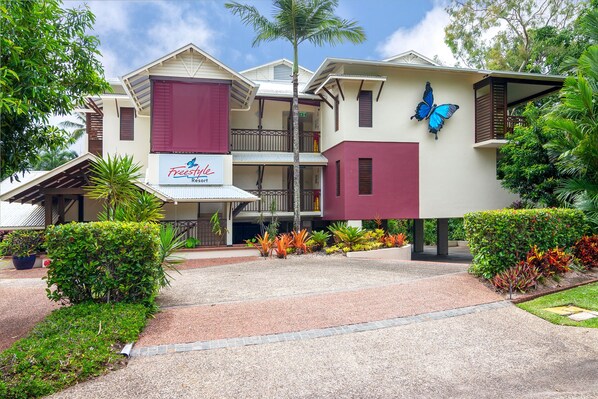 A hotel with a red and beige facade, a butterfly mural, and a sign for 'Freestyle Resort'. - Seascape Holidays 30 Tropic Style Two Bedroom Two Bathroom (Douglas)