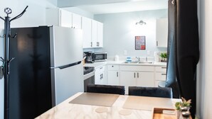 A modern kitchen with white cabinets, a black refrigerator, a microwave, and a sink. - AquaShores#3 - Pet friendly, BBQ grill & free Wifi (Ocean Shores)