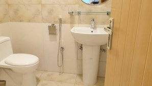 A small bathroom with a toilet, a shower, and a sink. - Orangeloft Kalabagh (Abbottabad)