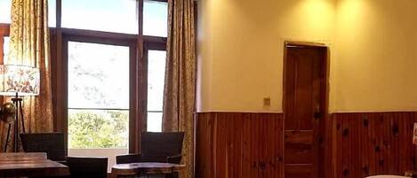 Una habitación de hotel con cama, escritorio, dos sillas y ventana con cortinas.