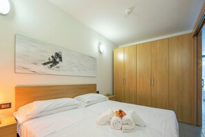 Ein Hotelzimmer mit einem großen Bett, einem Holzschrank, einem Bild an der Wand und einem Nachttisch mit einer Lampe.