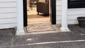A house entrance with a covered porch, a glass door leading to an interior with a sofa and a table. -  Luxury Town Square Condo king Bed & W/D (Blairsville)