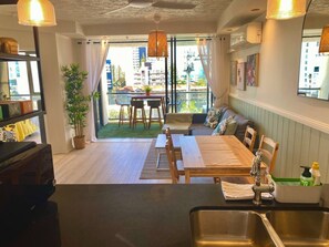 A modern kitchen with a sink, a dining area with a table and chairs, and a balcony with a view of the city.