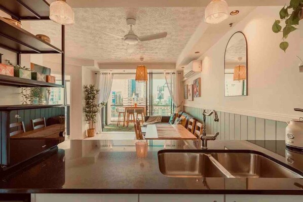 A modern kitchen with a central island, a dining area with a view, and a seating area with a plant.