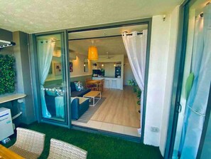 A modern interior with a sliding glass door leading to a living area, a kitchenette, and a dining space.