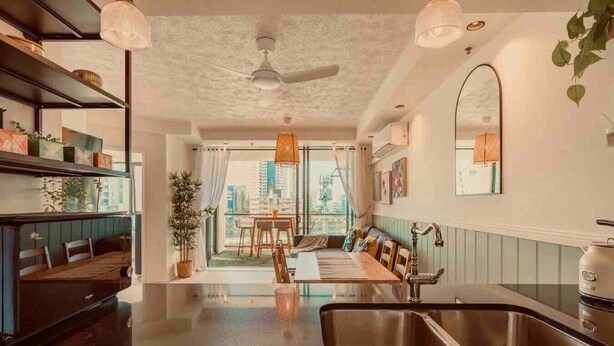 A modern kitchen with a central island, a dining area with a view, and a cozy seating area. - New Modern Deco' Apartment - Ocean View (Surfers Paradise)