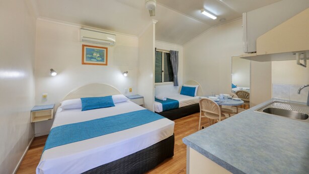 A compact hotel room with two beds, a small kitchenette, and a dining area. - 22 on Bowen Motel (Roma)