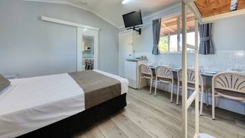 Ein Zimmer mit einem Bett, einem Schreibtisch mit Stühlen, einem Fernseher und einer Küchenzeile.