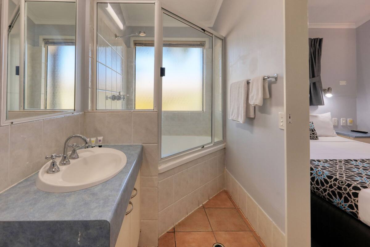 A bathroom with a sink, mirror, and shower.