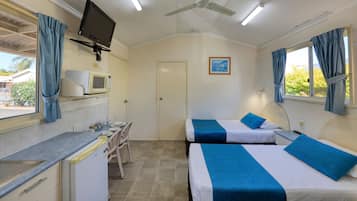 Een compacte hotelkamer met twee bedden, een kitchenette, een televisie en een raam met gordijnen.