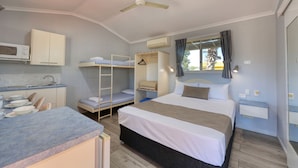 A compact hotel room with a bunk bed, a kitchenette, a single bed, and a window with curtains. - 22 on Bowen Motel (Roma)