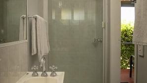 A modern bathroom with a glass-enclosed shower, a white sink, and a mirror. - 22 on Bowen Motel (Roma)