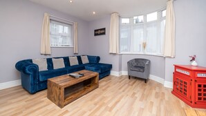 A living room with a blue sofa, a wooden coffee table, a grey armchair, and a red telephone cabinet.