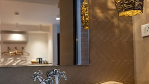 Een moderne badkamer met een rond wastafel, een spiegel en een hangende lamp.