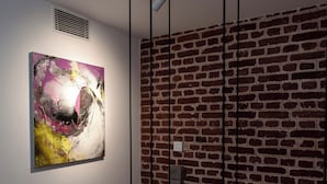 Een kamer met een bakstenen muur en een groot abstract schilderij.