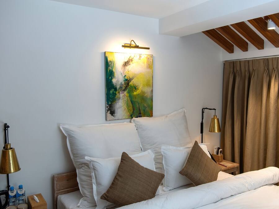 Habitación de hotel moderna con una cama grande, ropa de cama blanca y un cuadro abstracto de colores en la pared.
