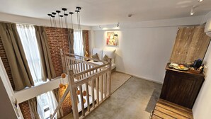 Een moderne loft slaapkamer met een hoogslaper, een houten trap en een eetgedeelte met een houten tafel en stoelen.