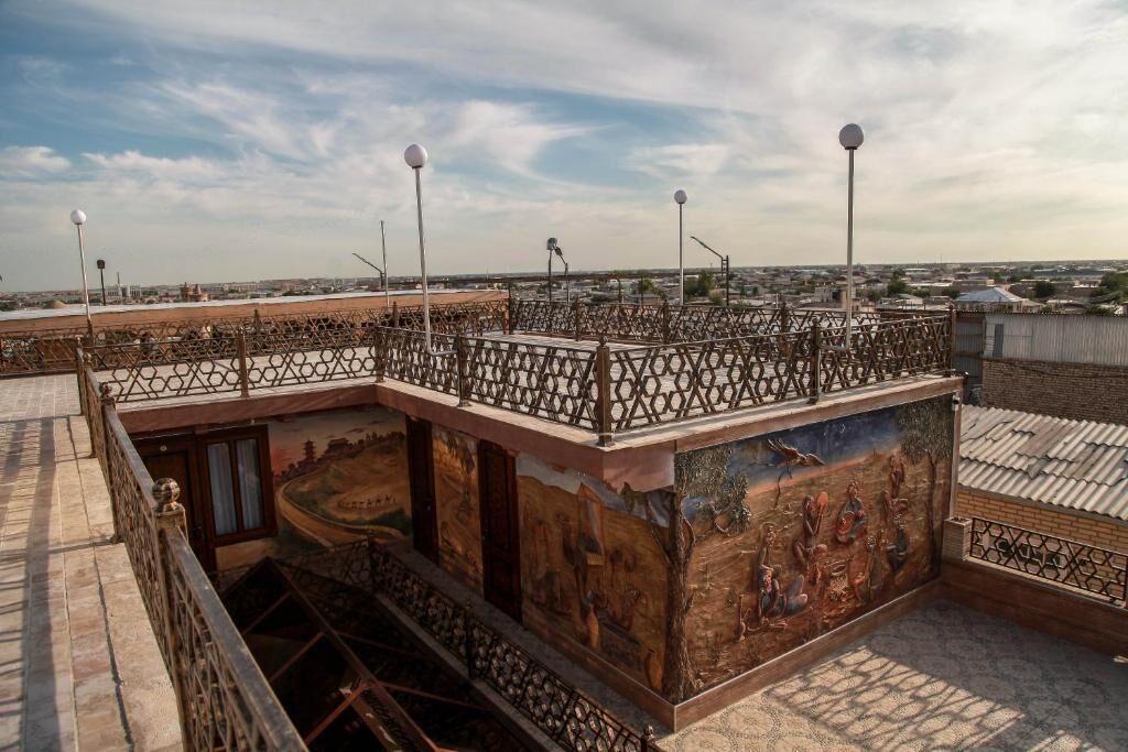 Terraço com guarda-corpo decorativo, um mural e luminárias de rua.