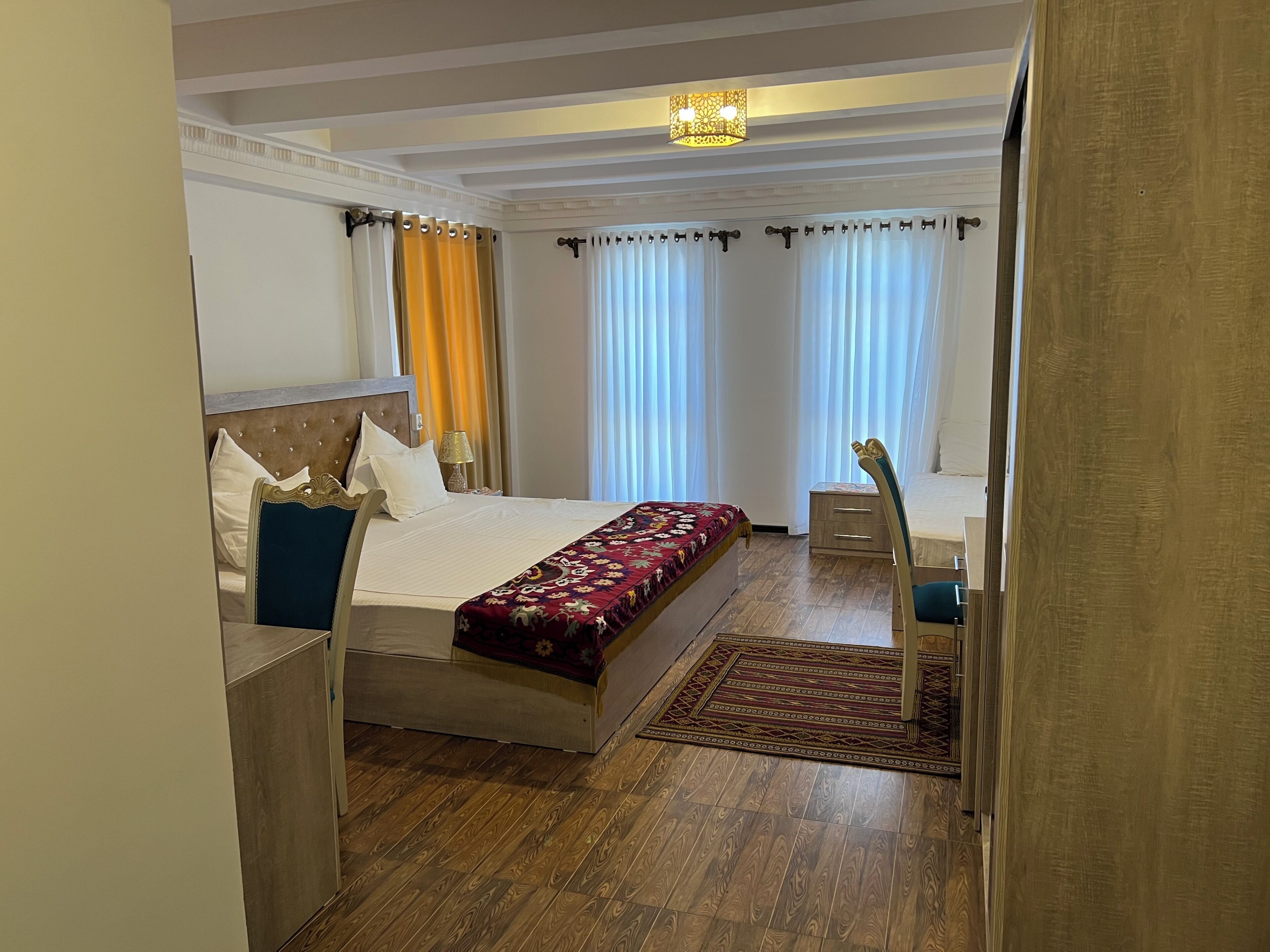 A hotel room with a bed, bedside tables, a chair, a rug, and curtains.