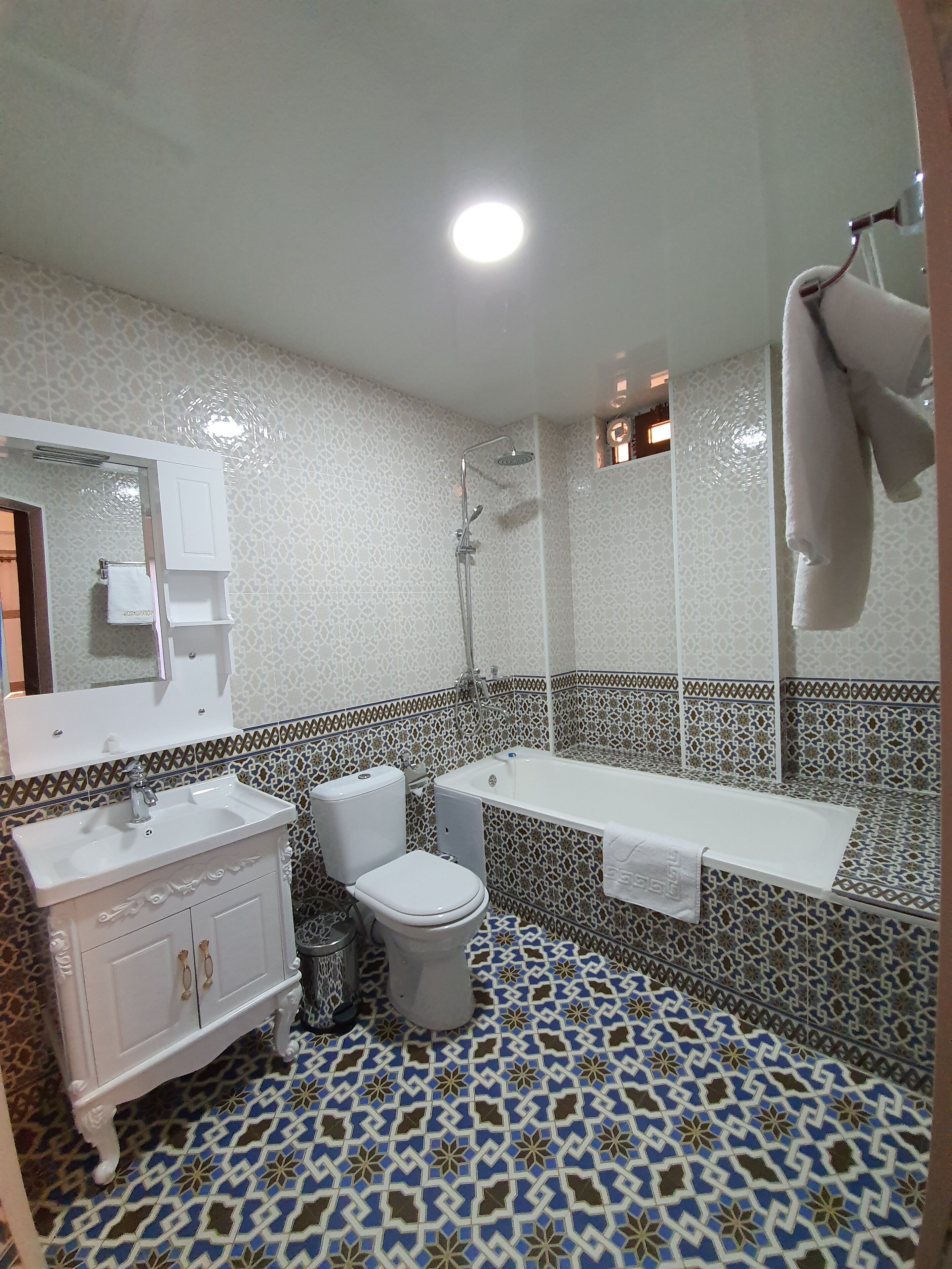 A bathroom with a white sink, toilet, and bathtub. The floor has a blue and white patterned tile design.