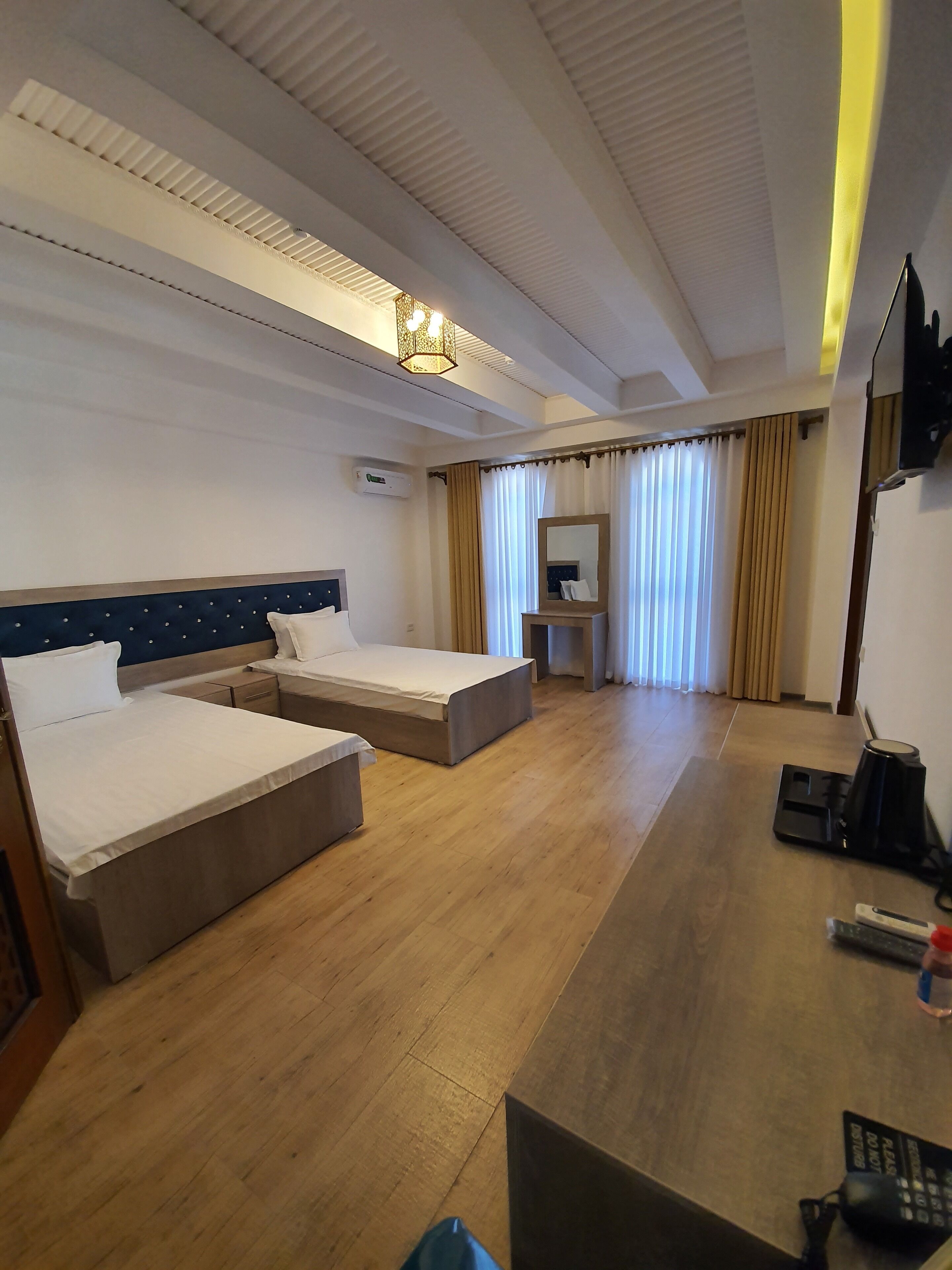 Une chambre d’hôtel avec deux lits, un bureau, une chaise, une télévision et une fenêtre avec des rideaux.