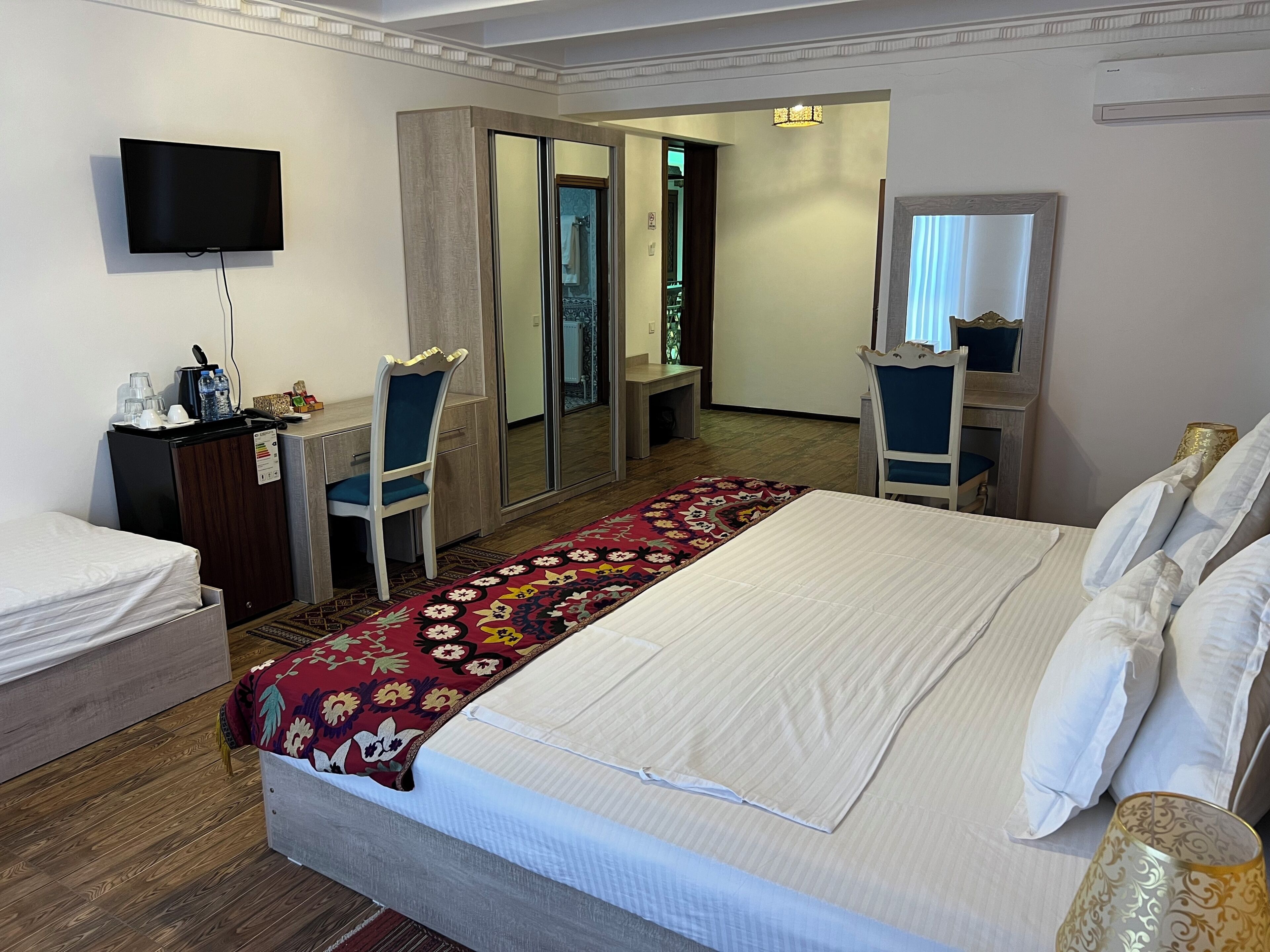 A hotel room with a bed, a desk with a computer, a TV, and a mirror.