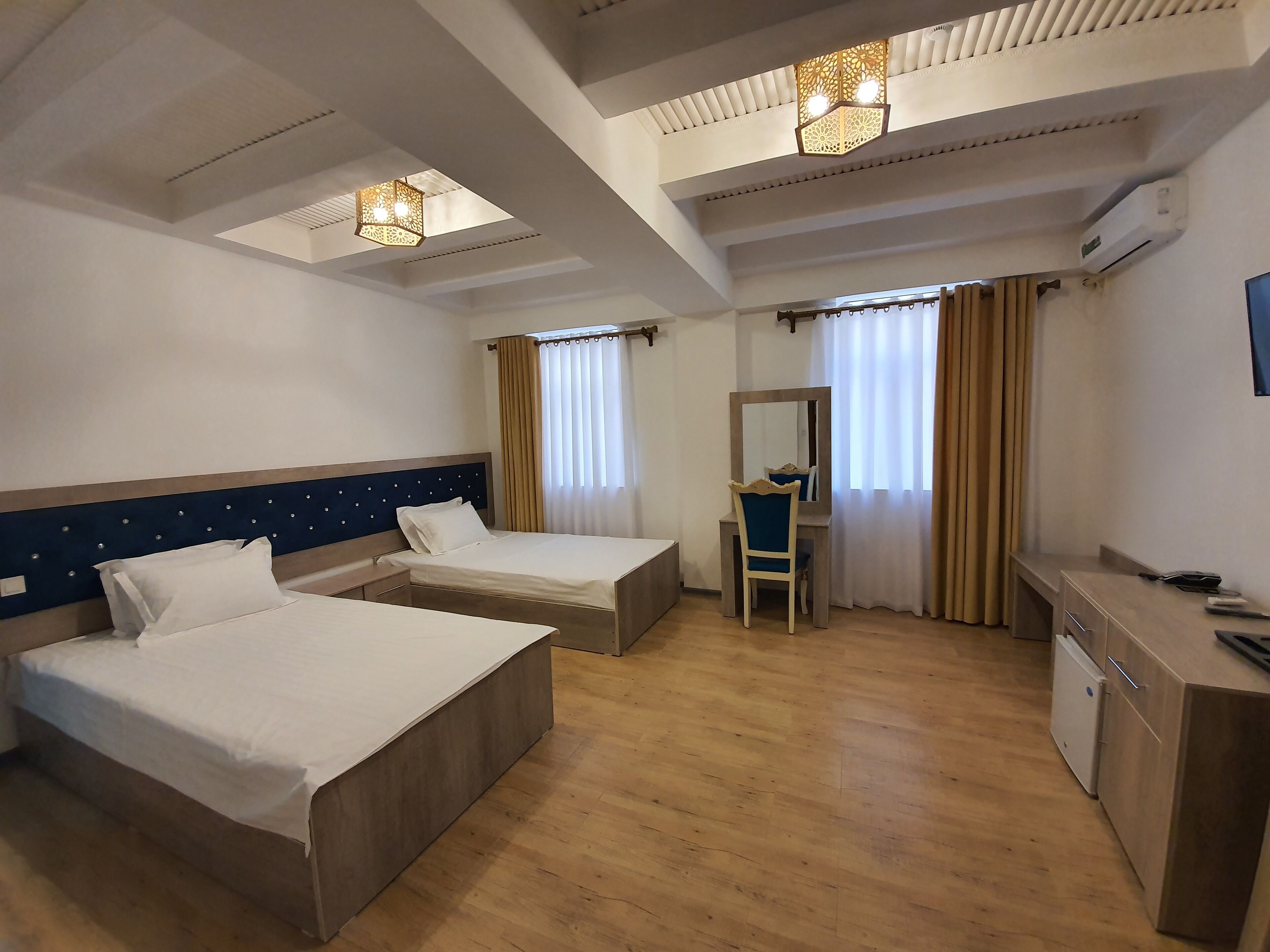A hotel room with two beds, a desk, a chair, and a mirror.
