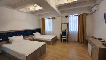 Une chambre d’hôtel avec deux lits, un bureau, une chaise et un miroir.