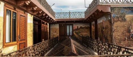 Un bâtiment doté d’un balcon, d’une fresque murale et d’une porte ornée de sculptures complexes.