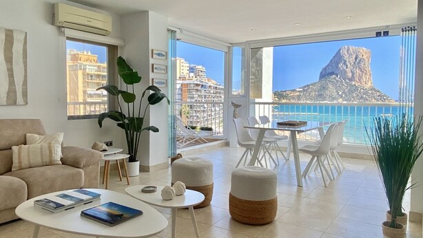 Un salon spacieux avec balcon donnant sur la mer, comprenant un canapé, une table basse et un coin repas.