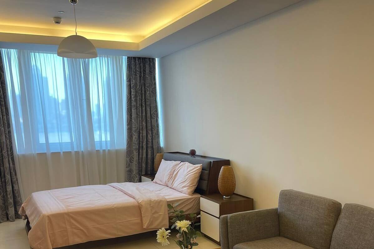 A modern bedroom with a bed, a sofa, a coffee table, and a nightstand.