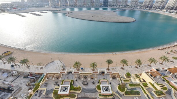 A resort with a pool, palm trees, and a beach. - VB22 & VB23 by Qatar Coral (Doha)