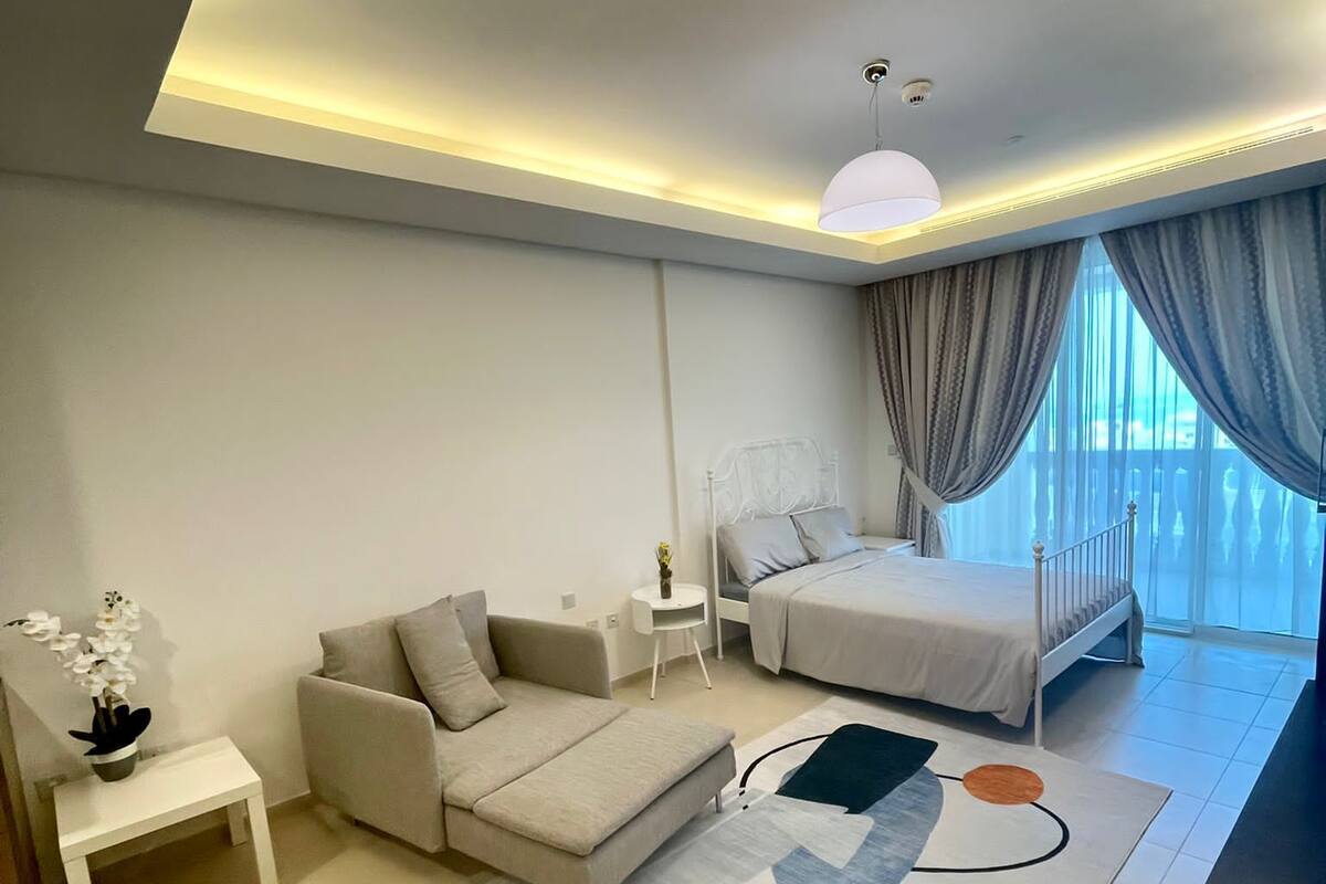 A modern bedroom with a bed, a sofa, a small table, and a decorative rug.